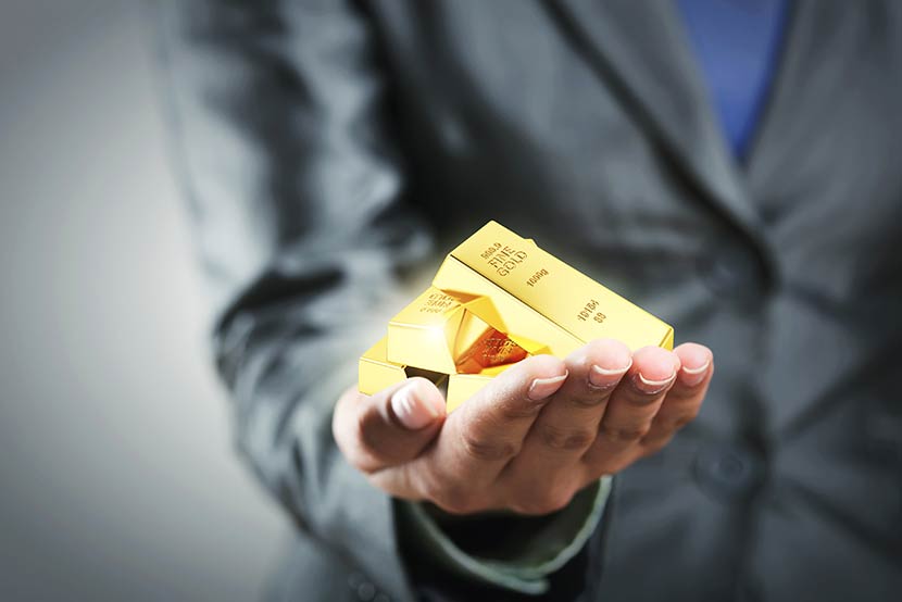 Professional business man holding gold bars, making a case for buying gold despite market conditions
