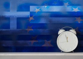 Greek flag juxtaposed over European Union flag with white retro clock sitting in front, moments away from unrest