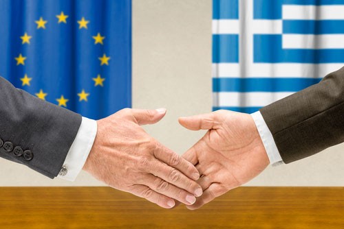 Greece and European Union strike a deal after marathon talks, as illustrated by two hands extending for a handshake