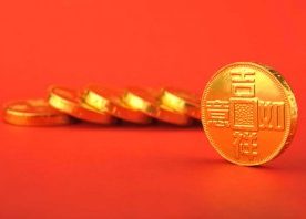 Fallen stack of Chinese gold coins against bright red backdrop