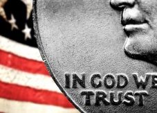 Magnified words on U.S. quarter, In God We Trust, against backdrop of American flag