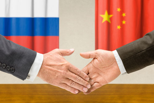 Two hands extending towards one another, representing Russia and China shaking hands