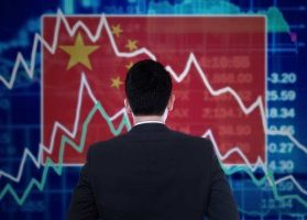 Chinese businessman staring at stock market screen as China stock trading halts after steep drop