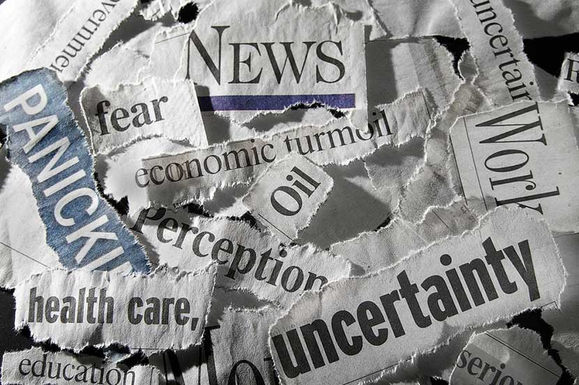 Torn pieces of newspaper with words like uncertainty, health care, oil, economic turmoil, and panic