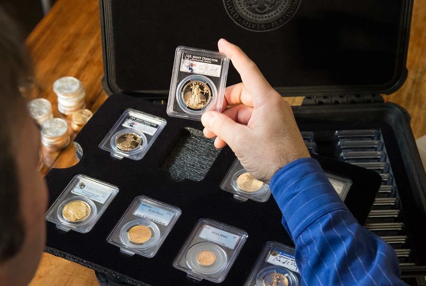 Man inspecting his collection of certified gold and silver coins in slab cases