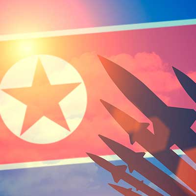 North Korea flag in sky with black missiles shooting into the sky
