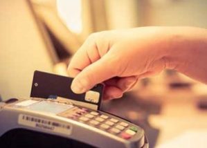 hand swiping credit card through credit card machine