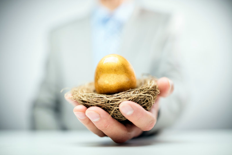 Businessman holding out nest with golden egg