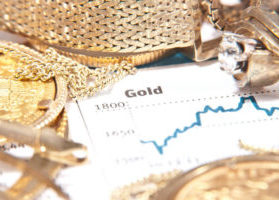 Gold chart surrounded by gold coins and jewelry