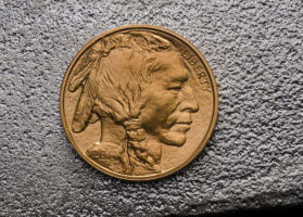 Indian head on Gold American Buffalo Coin against silver backdrop