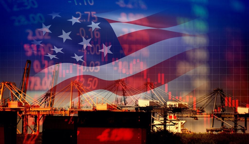 US ports and manufacturing facilities in foreground over US. flag and stock graphs