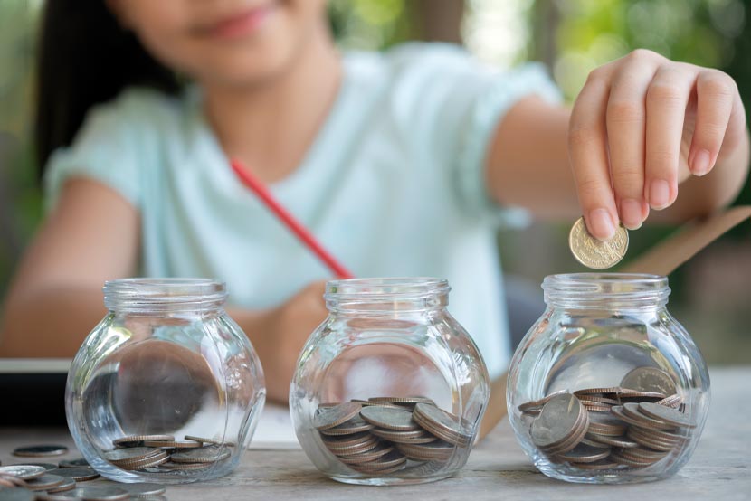 Girl putting coins into multiple jars