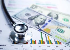 Stethoscope and U.S. dollars on charts and research data