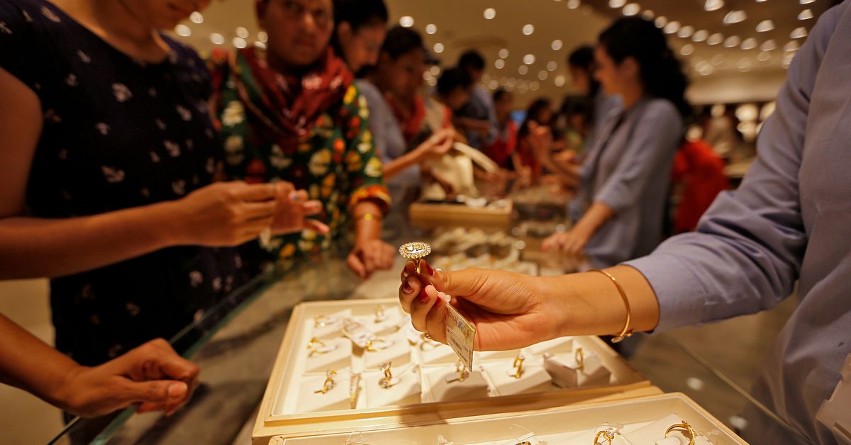 Individuals examining gold jewelry at a convention or tradeshow