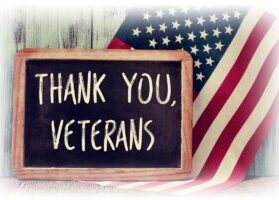 Chalkboard reading “THANK YOU, VETERANS” by American flag