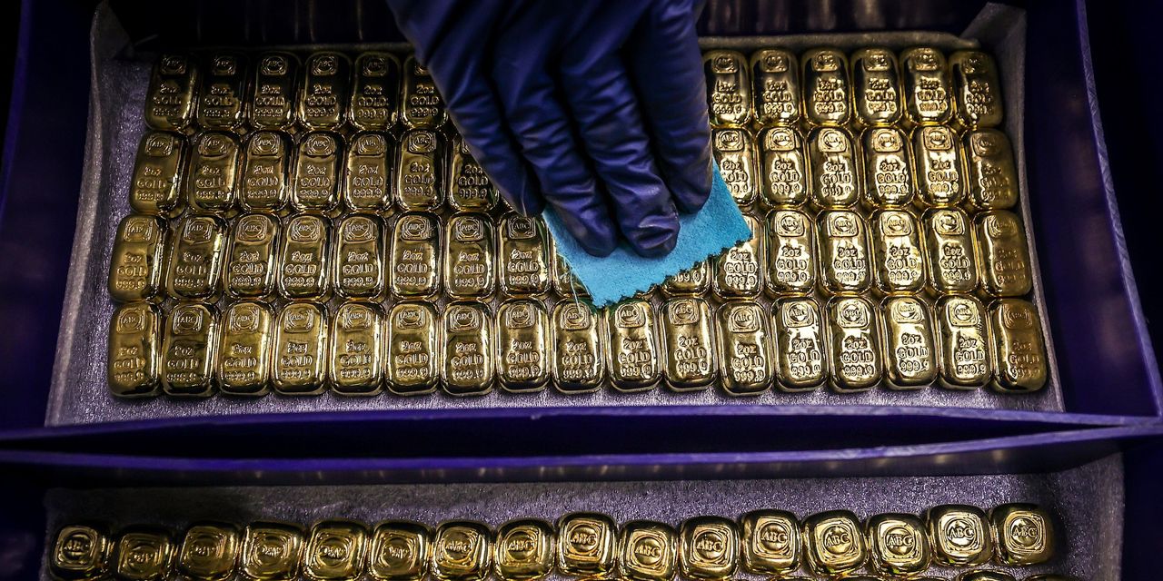 Gold bars being polished with a gloved hand.