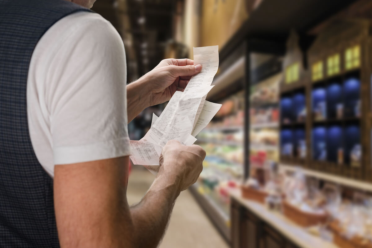 Man in grocery aisle looking at receipts