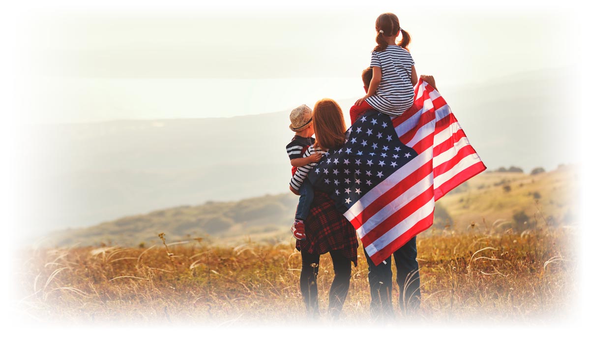 Happy family with an American flag at sunset outdoors