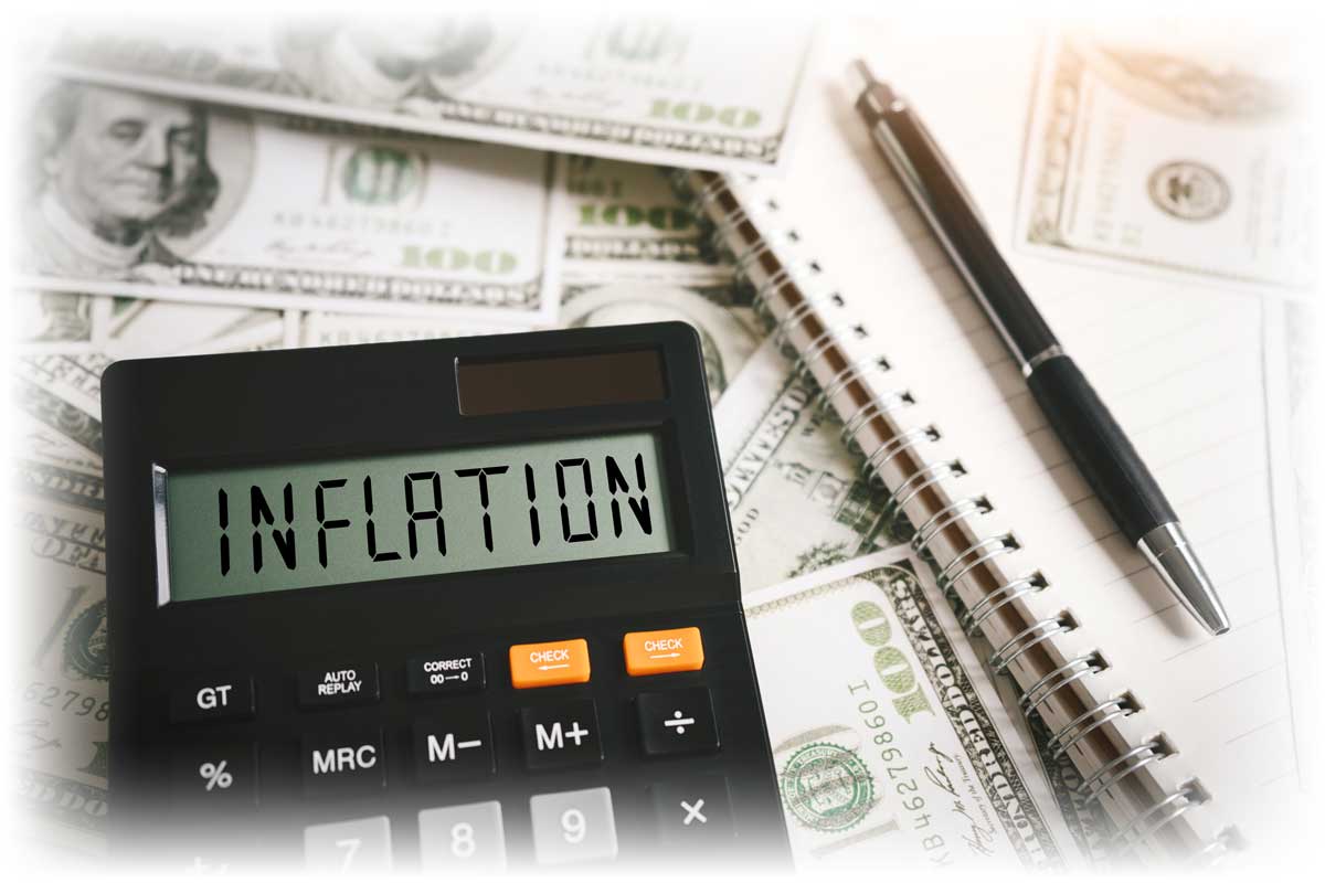 Calculator reading “INFLATION” over pen, notebook, and $100 notes