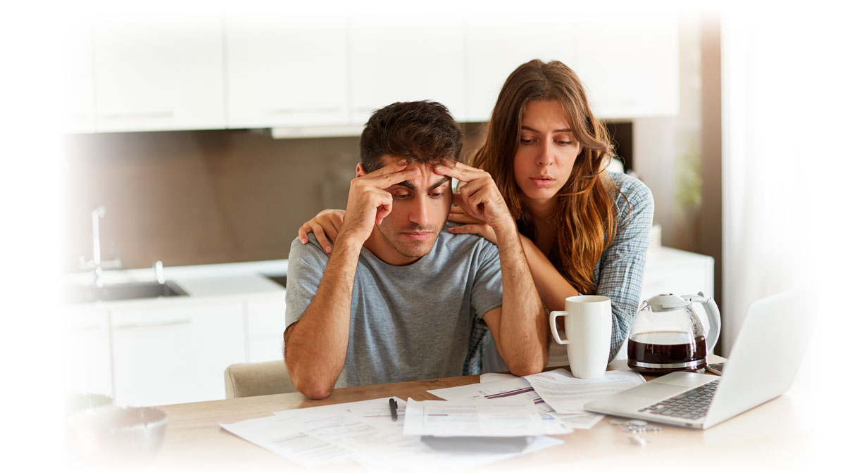Couple looking stressfully at paperwork and laptop