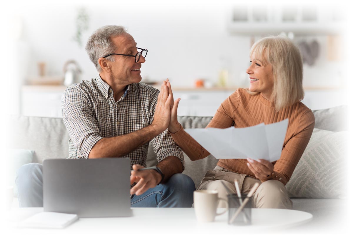 Middle-aged couple sharing high-five in front of laptop