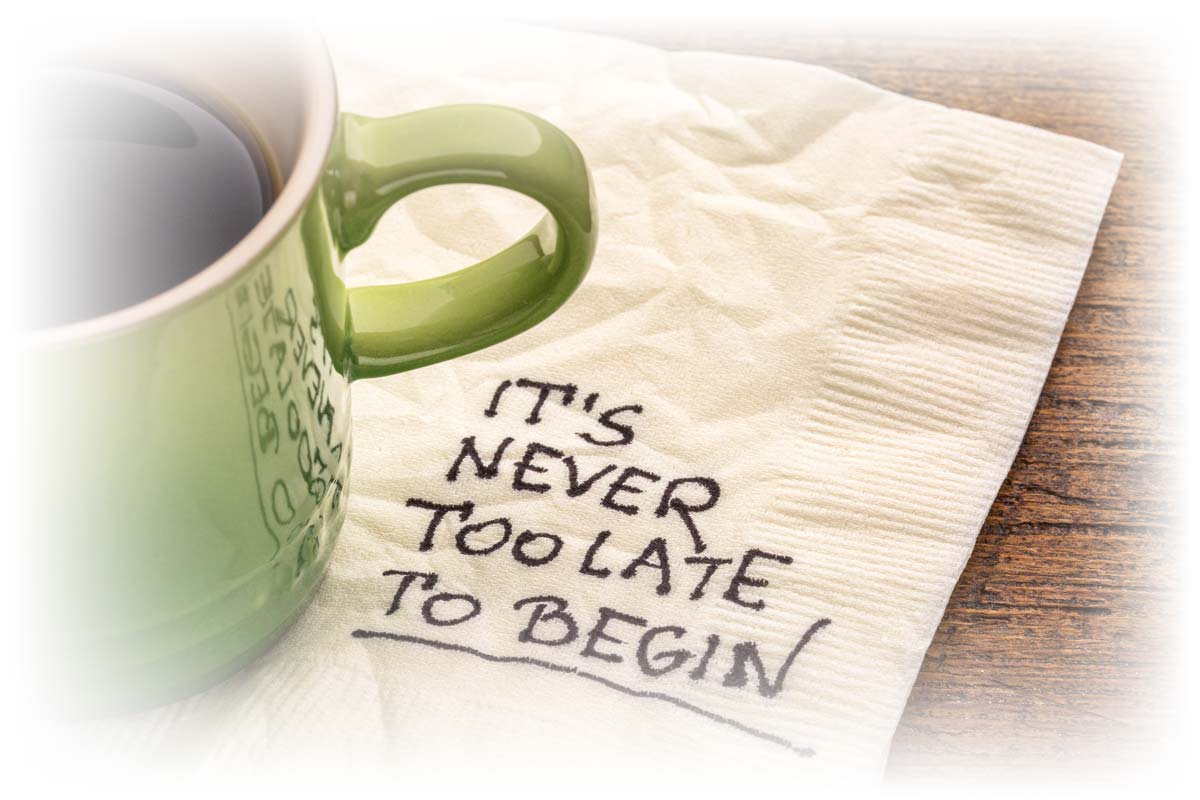 Coffee cup on top of napkin that reads “IT’S NEVER TOO LATE TO BEGIN”