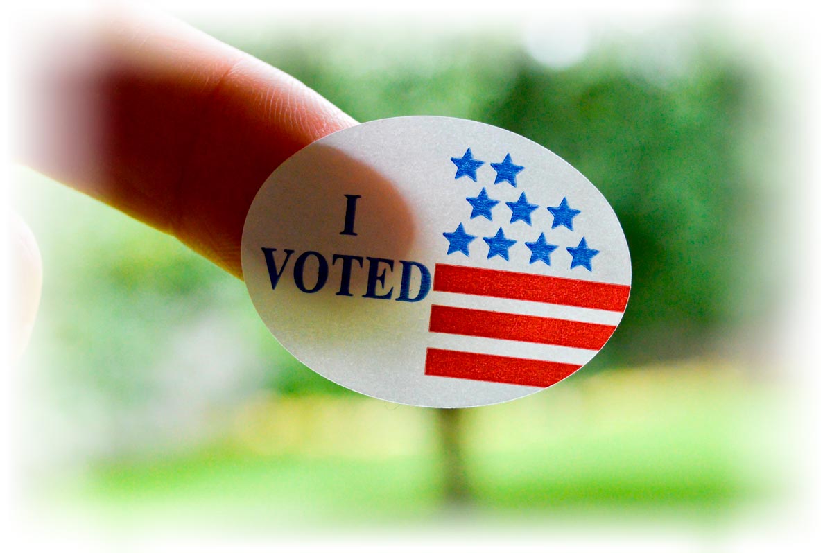 Finger holding up "I VOTED" sticker