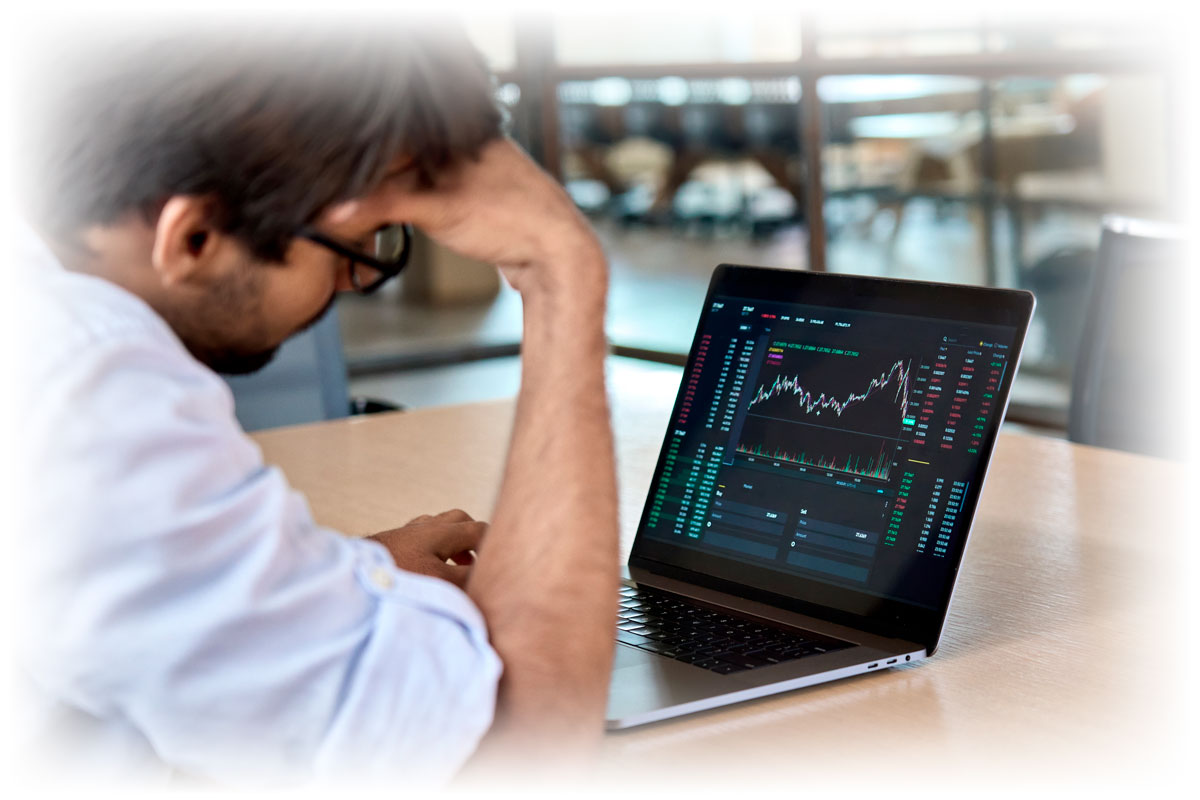 Man looking at laptop showing negative market data