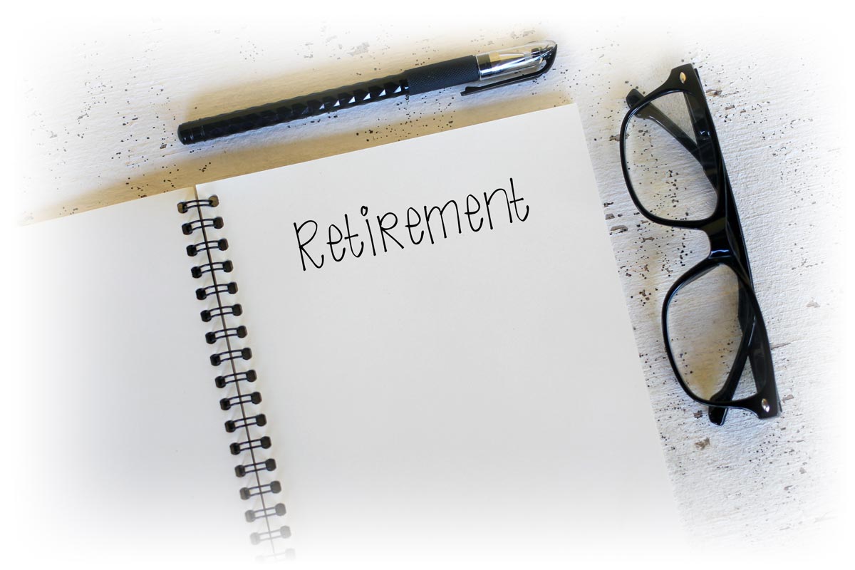 Notepad reading "RETIREMENT" next to glasses and pen