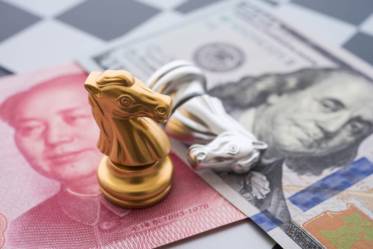 Chinese yuan note and U.S. $100 note below chess pieces