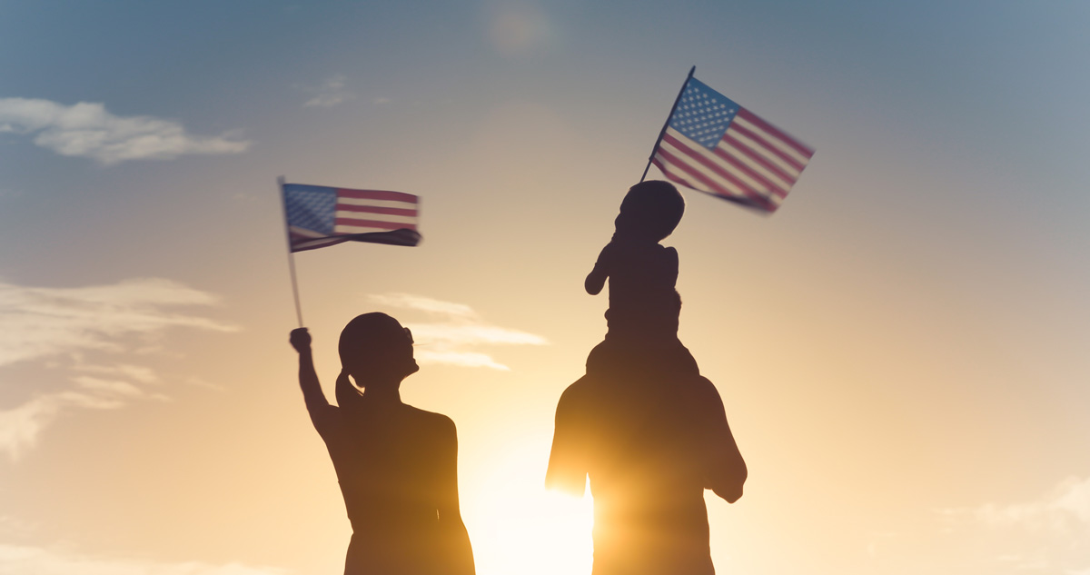 Family in silhouette holding American flags