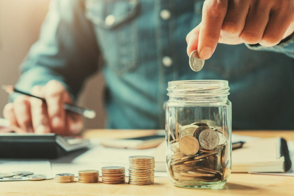 Increasingly large stacks of coins leading to jar full of coins