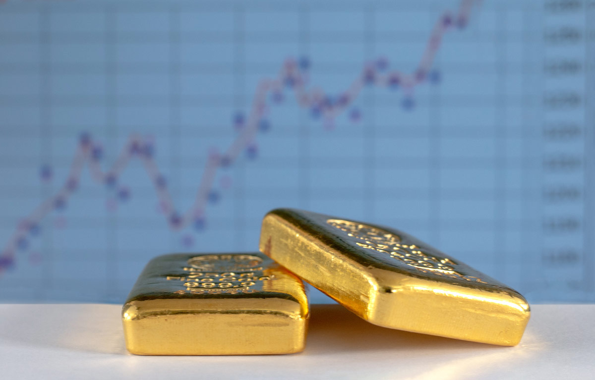 Gold bars in front of upwards-trending data chart