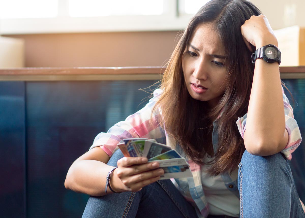 Young woman looking stressfully at credit cards