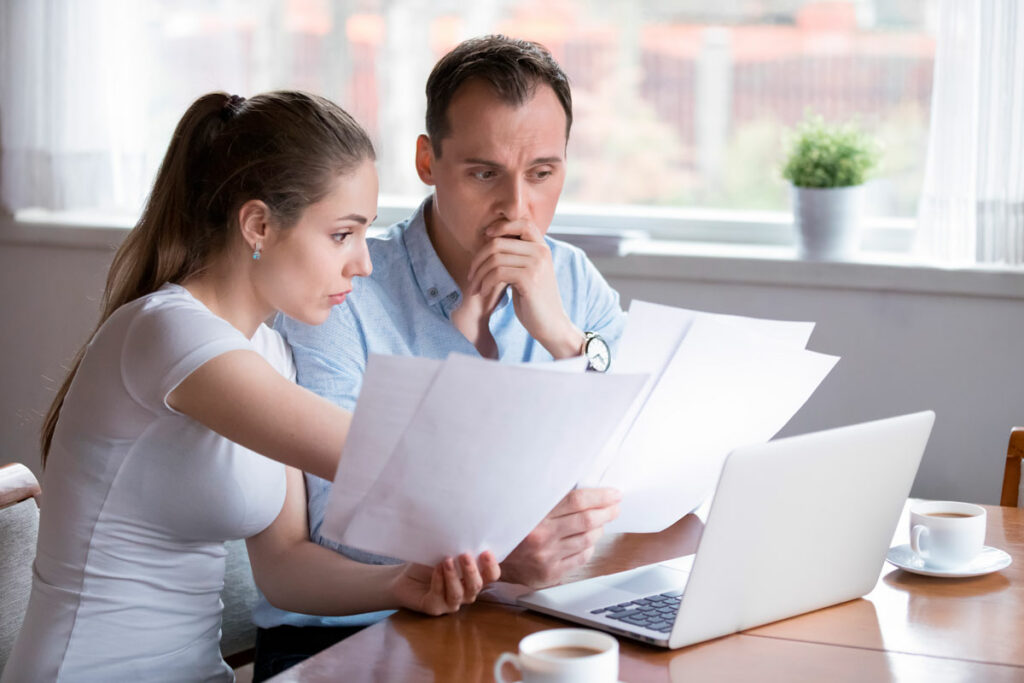Stressed couple looking over documents and laptop