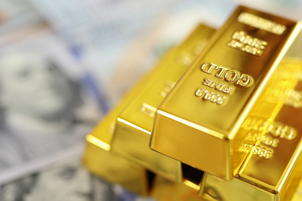 Gold bars on pile of $100 notes