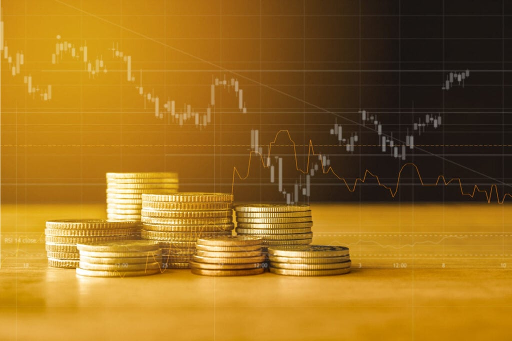 Stacks of gold coins in front of economic data