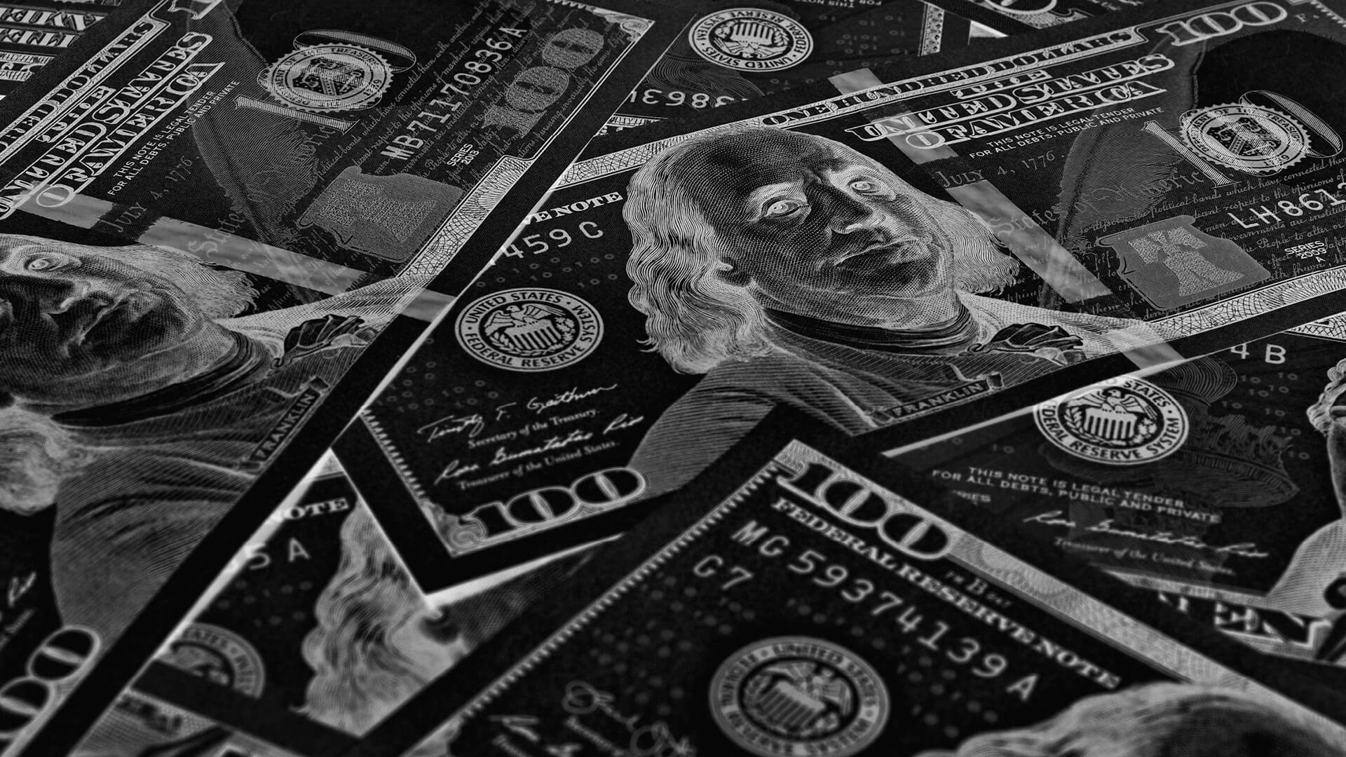 Dark inverted close-up of scattered $100 bills.